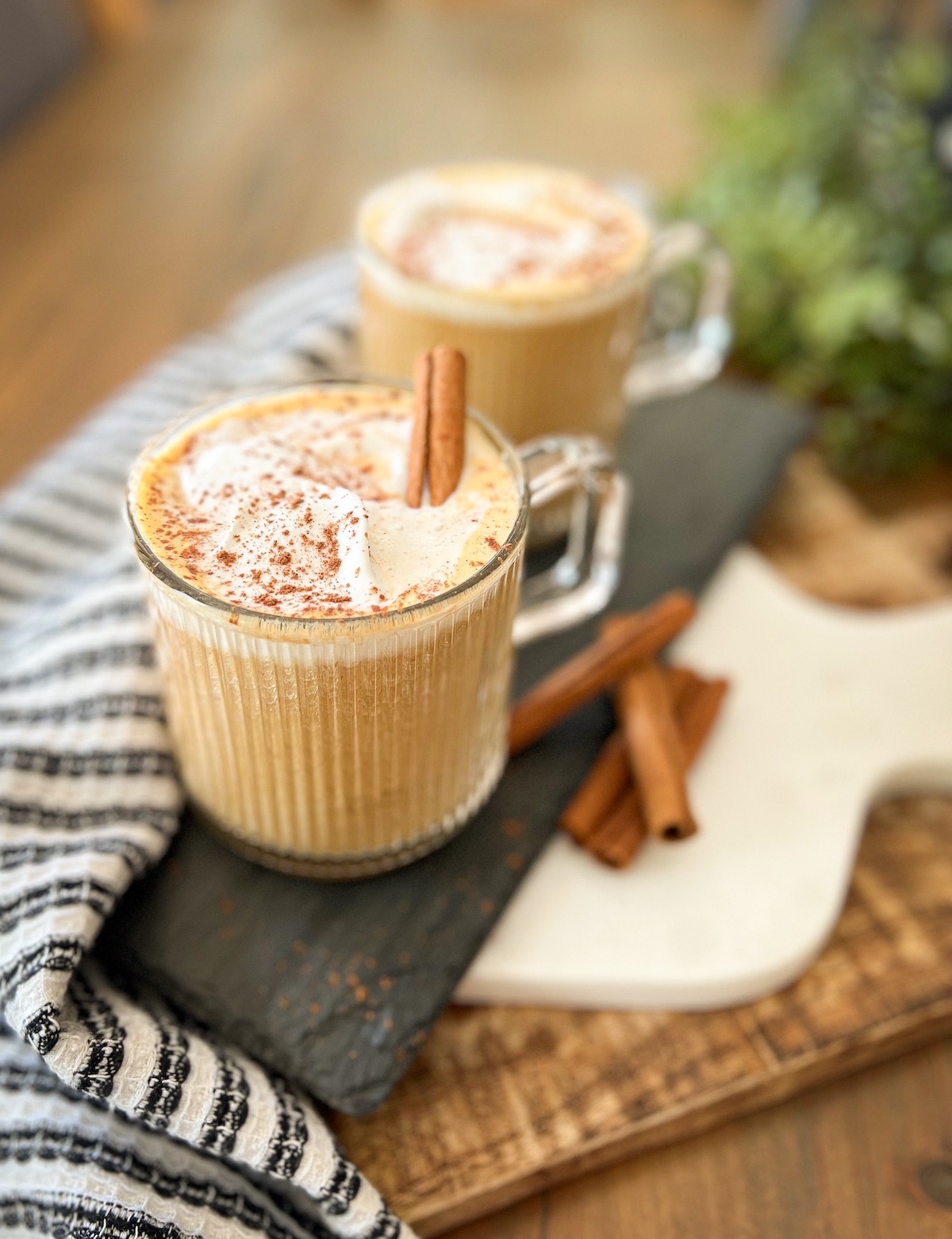 close up image of pumpkin spice latte with coconut whipped cream and a cinnamon stick