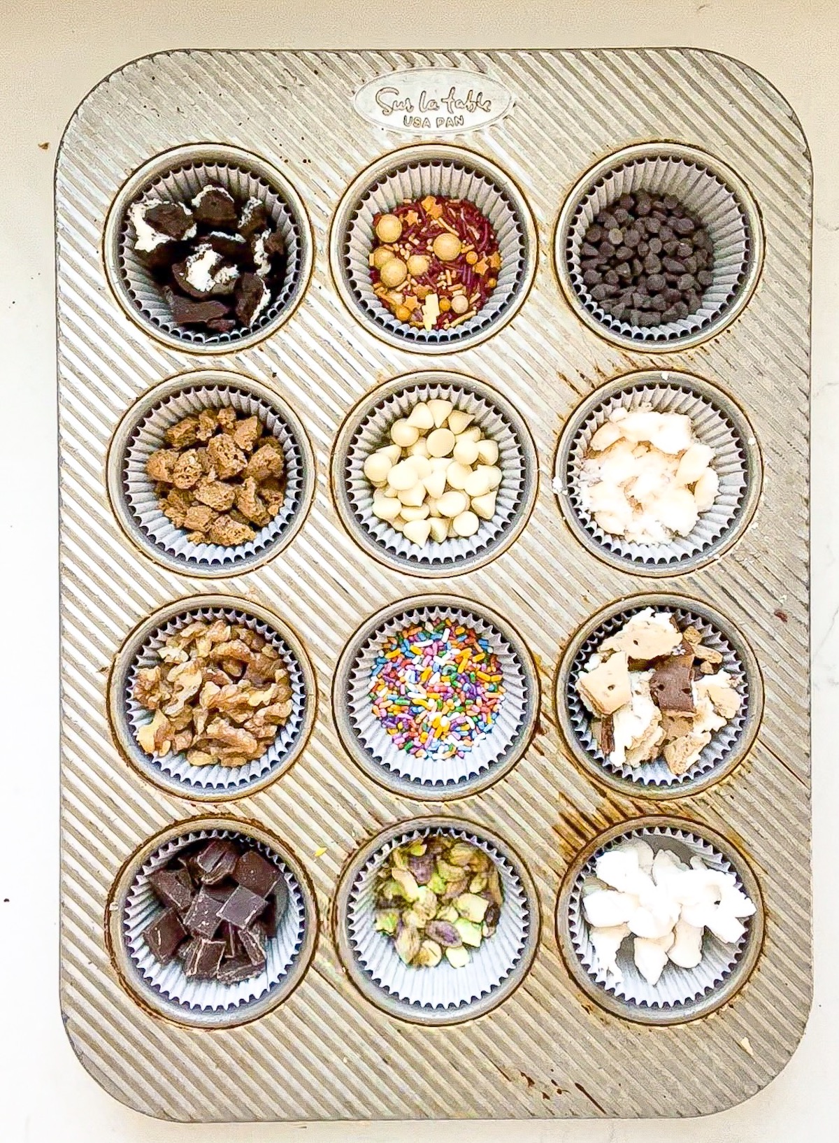 toppings for caramel apples arranged in a muffin tin
