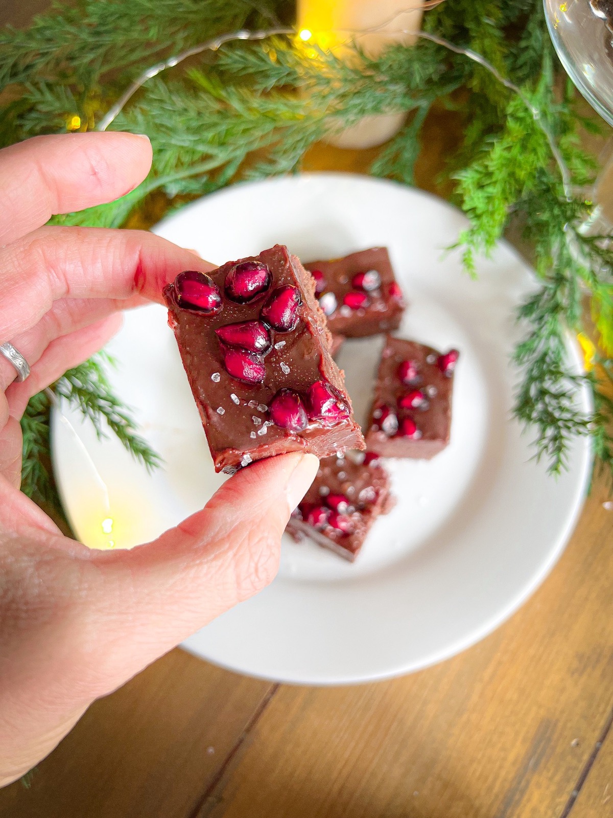 up close photo of a square of spiced fudge topped with pomegranate seeds and sea salt