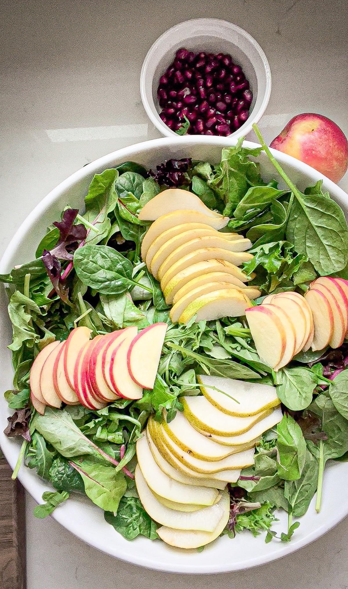 sliced fruit on top of mixed greens