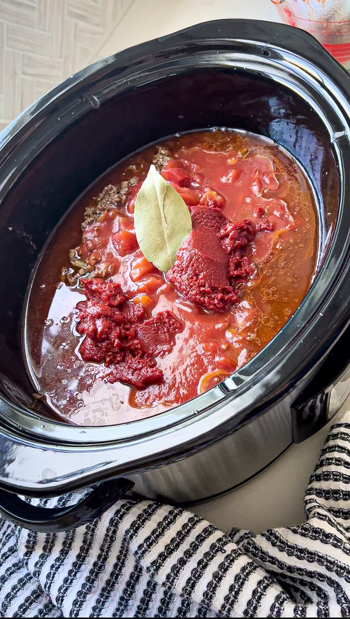 chili ingredients in a slow cooker with a bay leaf